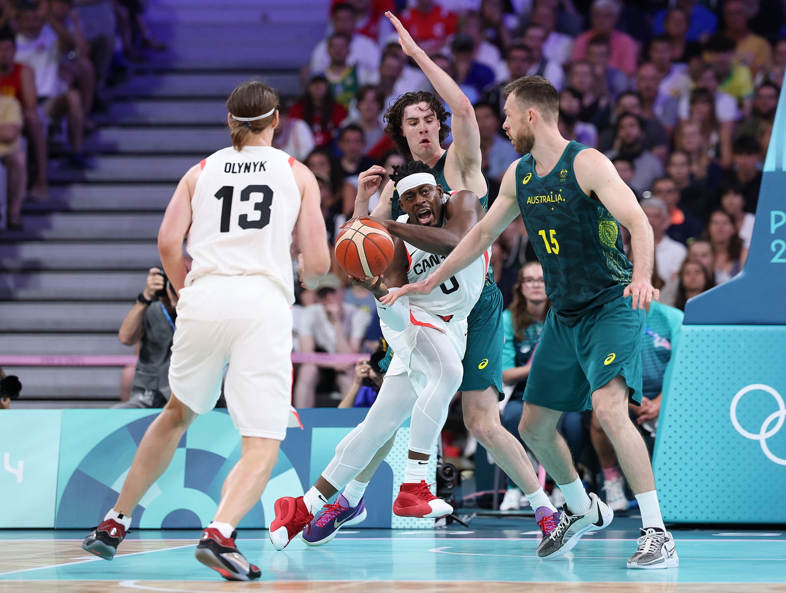 Luguentz Dort of Canada closely guarded by multiple Australian players at a highly attended basketball Olympics match