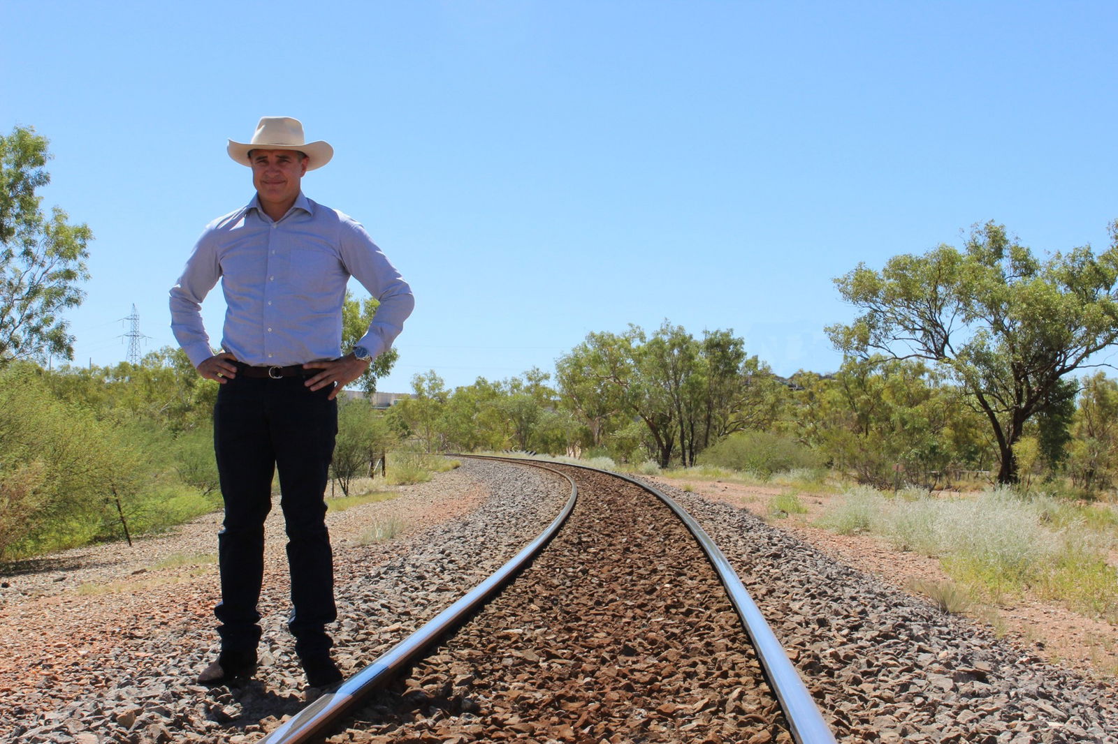 A man in a cowboy hat stands on a rail line in Queensland.