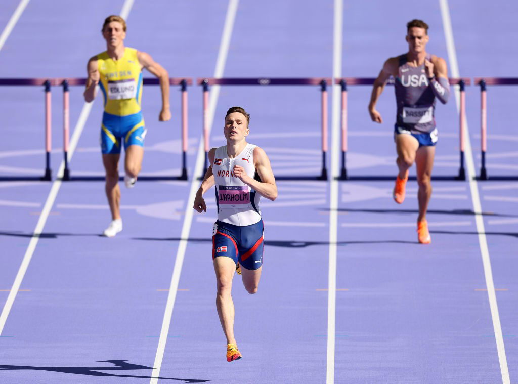 Karsten Warholm runs to victory in the 400m hurdles at the Paris Olympics. Runners from Sweden and USA are seen trailing him.