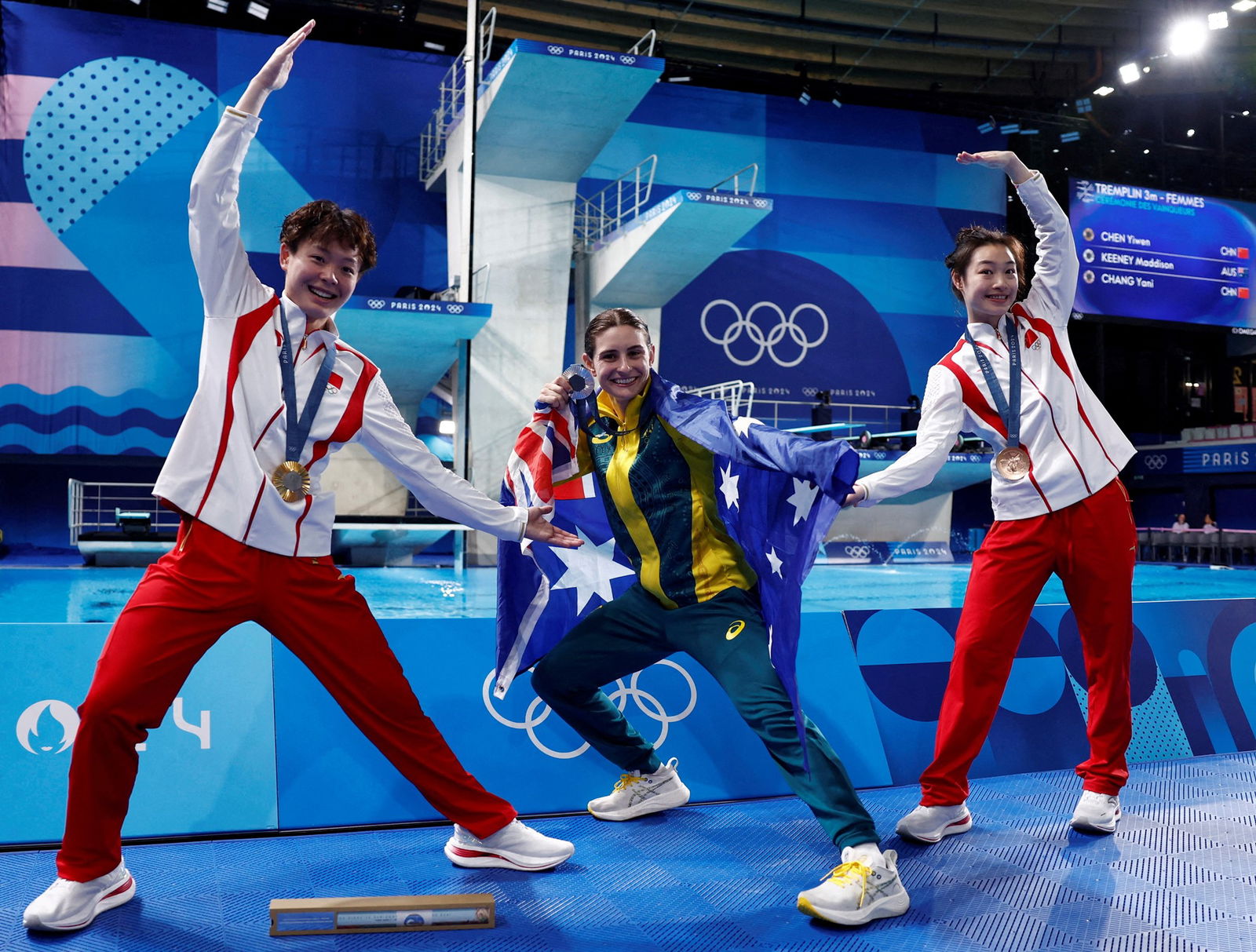 Two Chinese divers pose with their arms towards an Australian diver during a medal ceremony