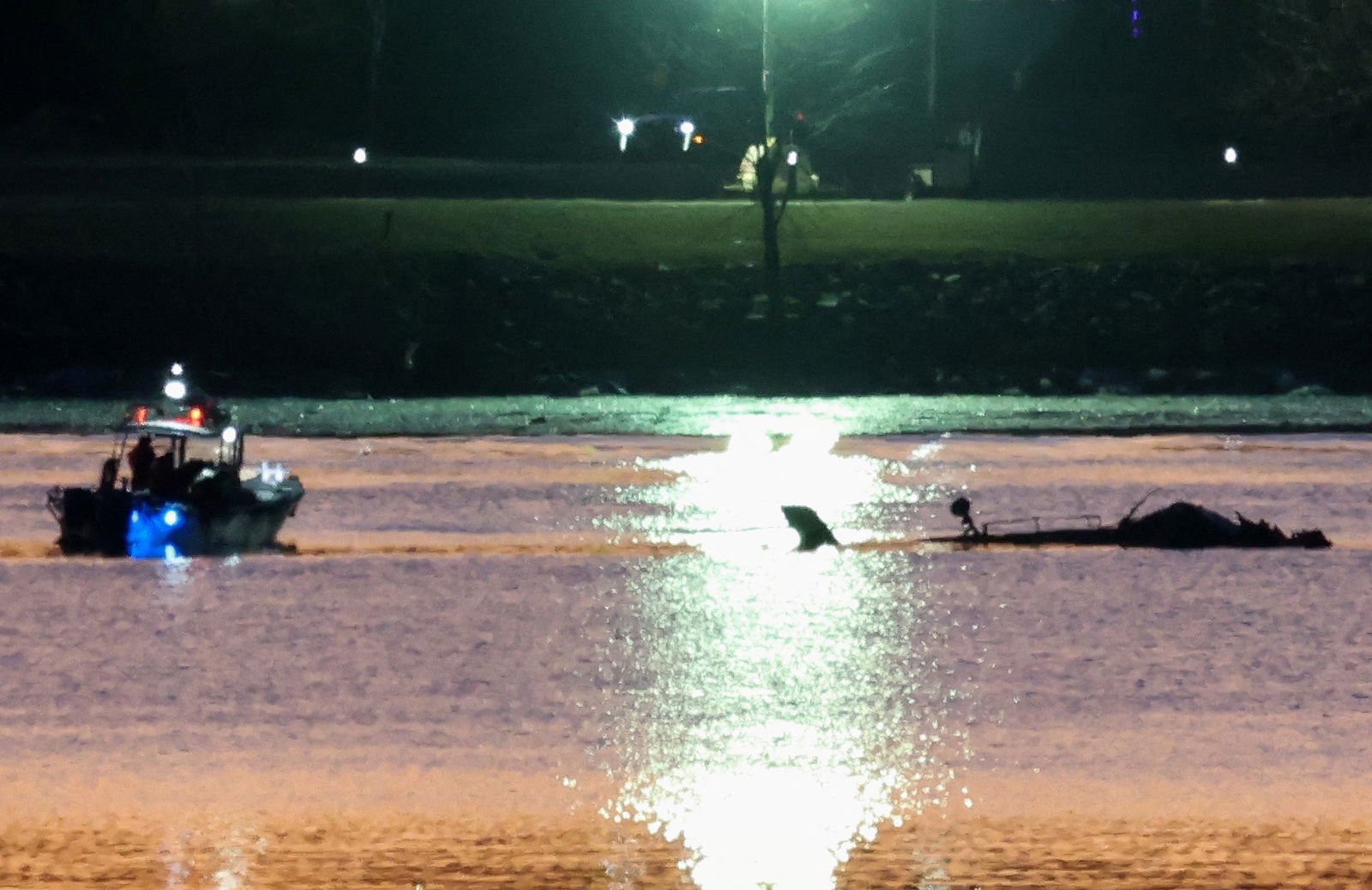 Rescuers on a boat work next to the wreckage of a Black Hawk helicopter