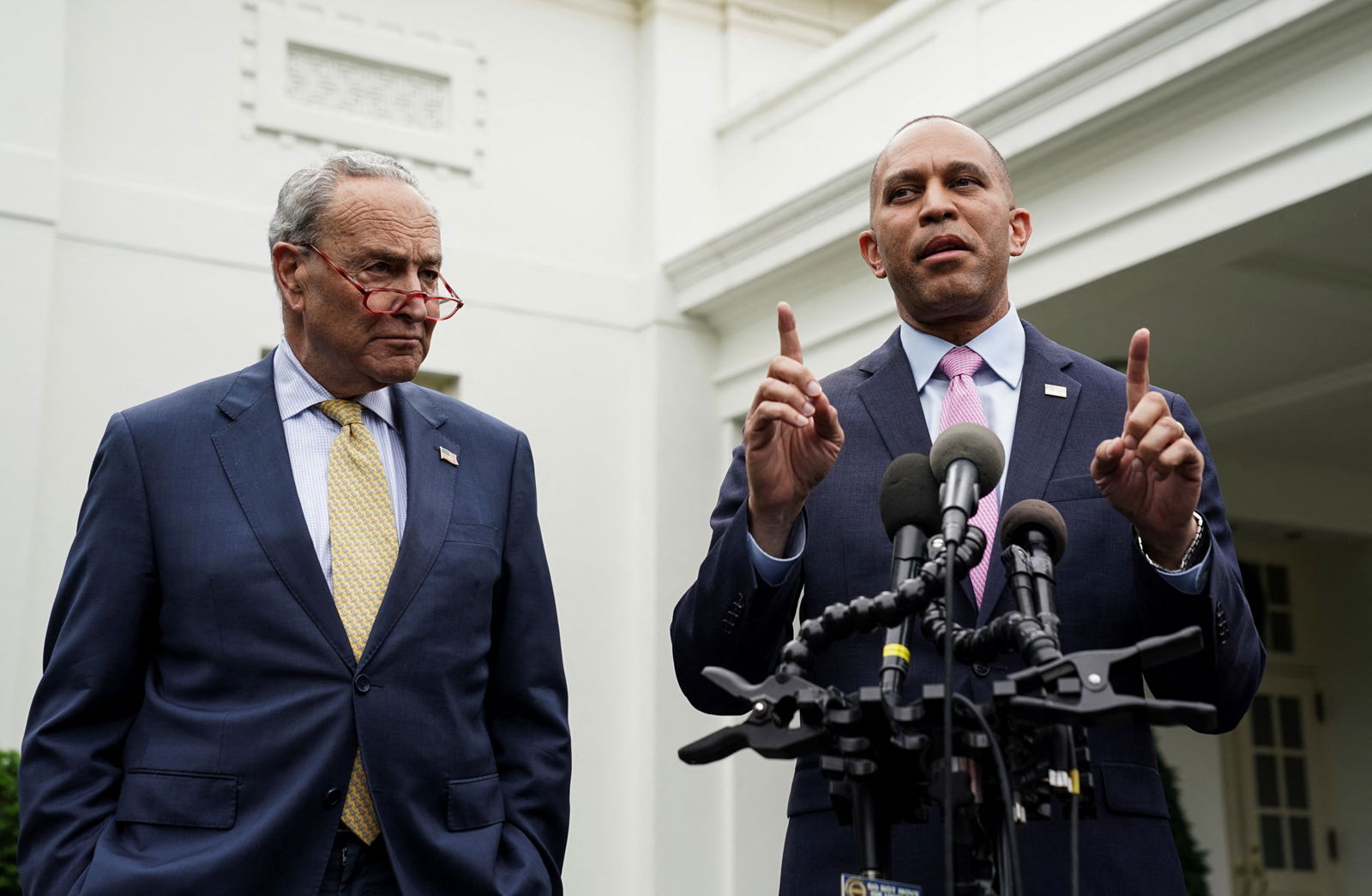 Chuck Schumer watches on as Hakeem Jeffries speaks at a stand of microphones outside the White House.