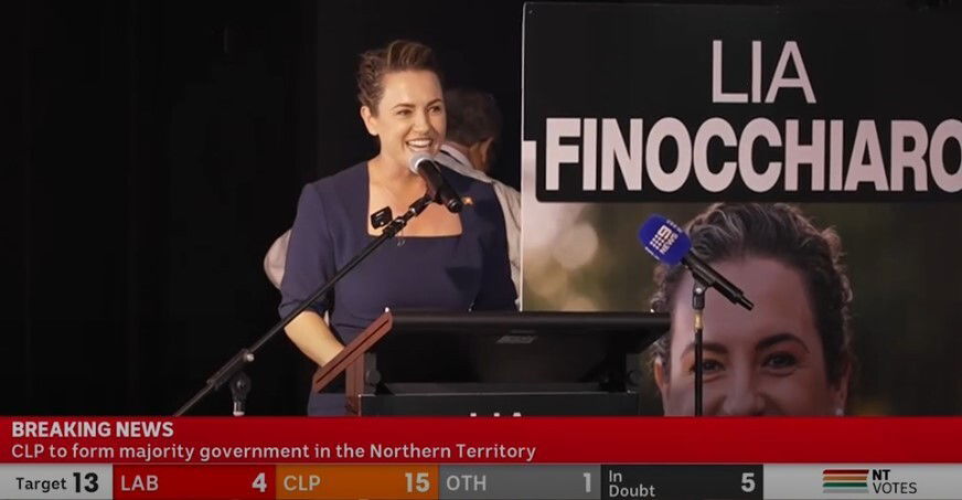 a brunette woman speaking at a lectern