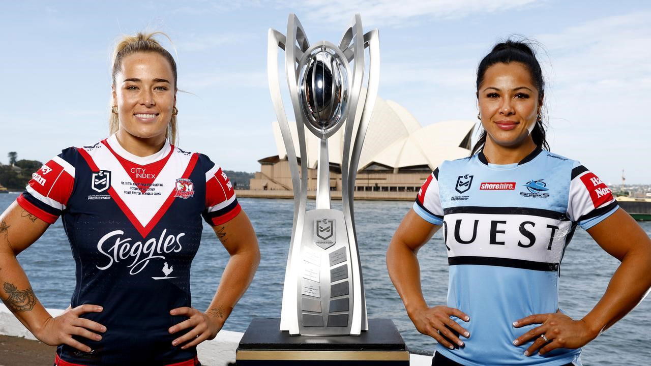 Isabelle Kelly and Tiana Penitani stand either side of the NRLW premiership trophy.