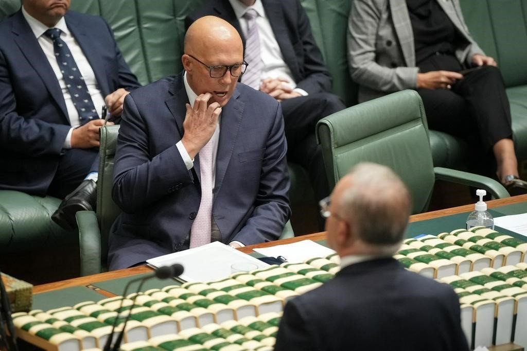 Peter Dutton stratches his face as he sits in the House of Representatives.
