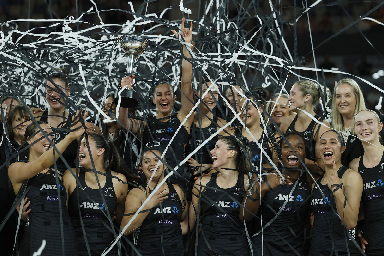 Players are covered in streamers as they huddle together and lift a trophy