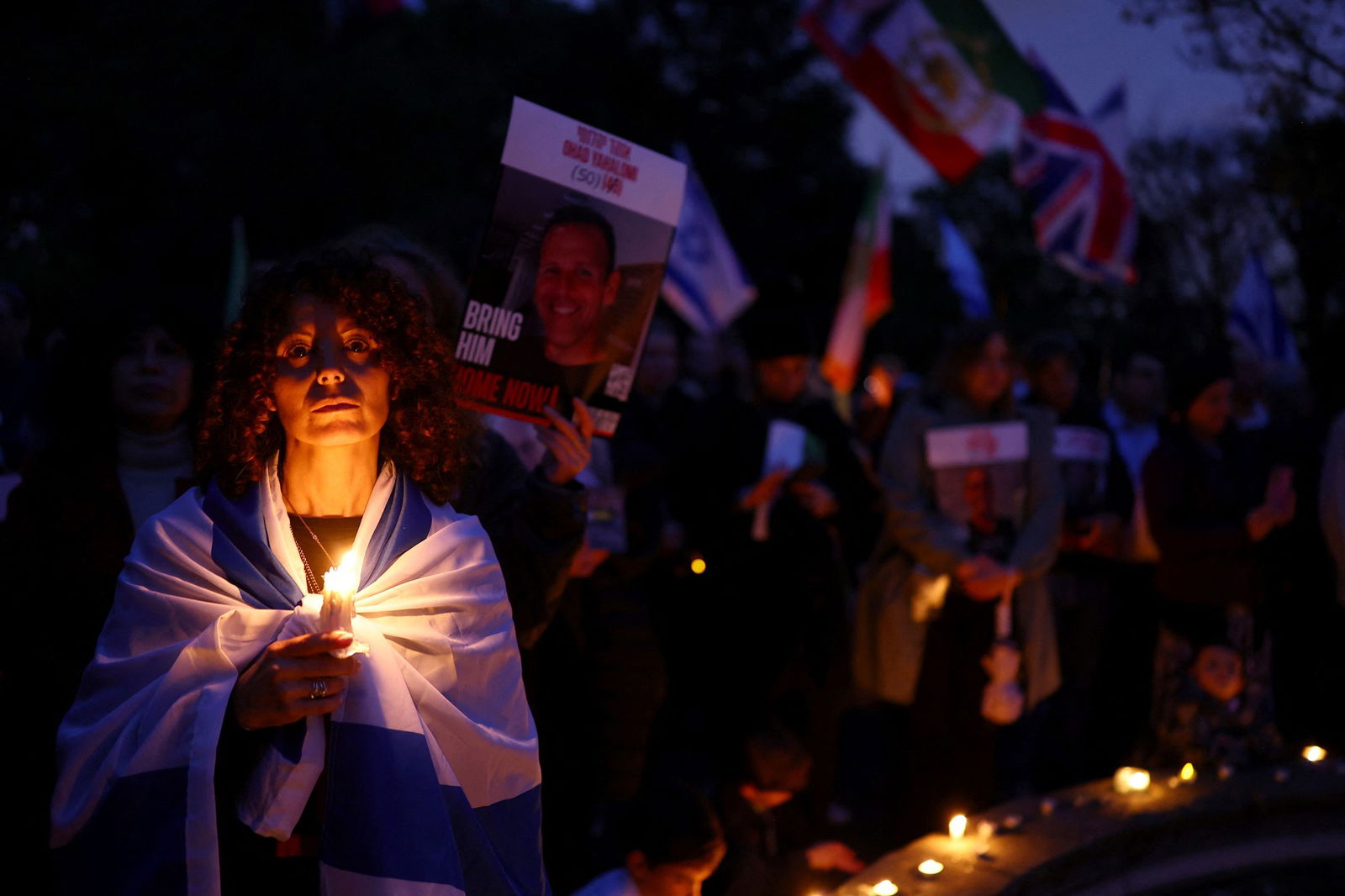 A woman holds a candle in a crowd. 