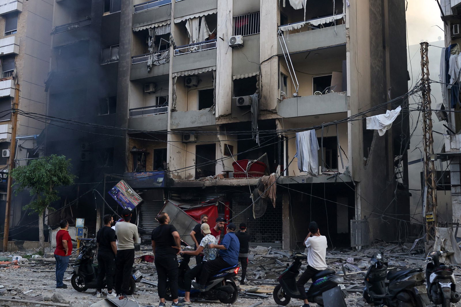 People stand outside damaged apartment building