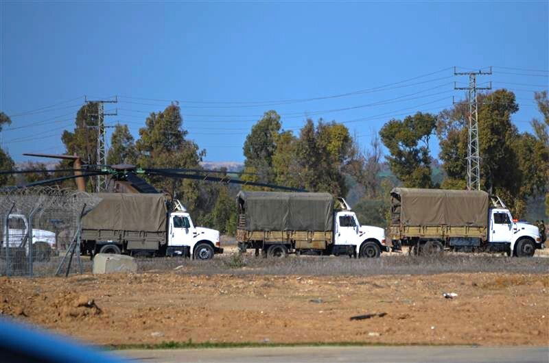 Several trucks parked in front of helicopters.