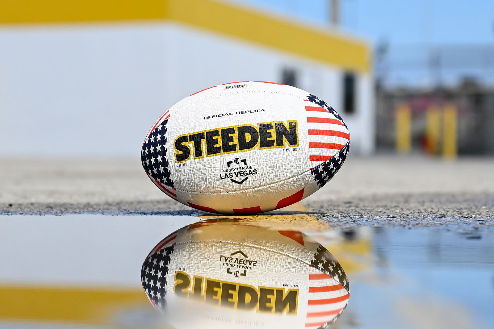 An American themed NRL ball reflected in a puddle.