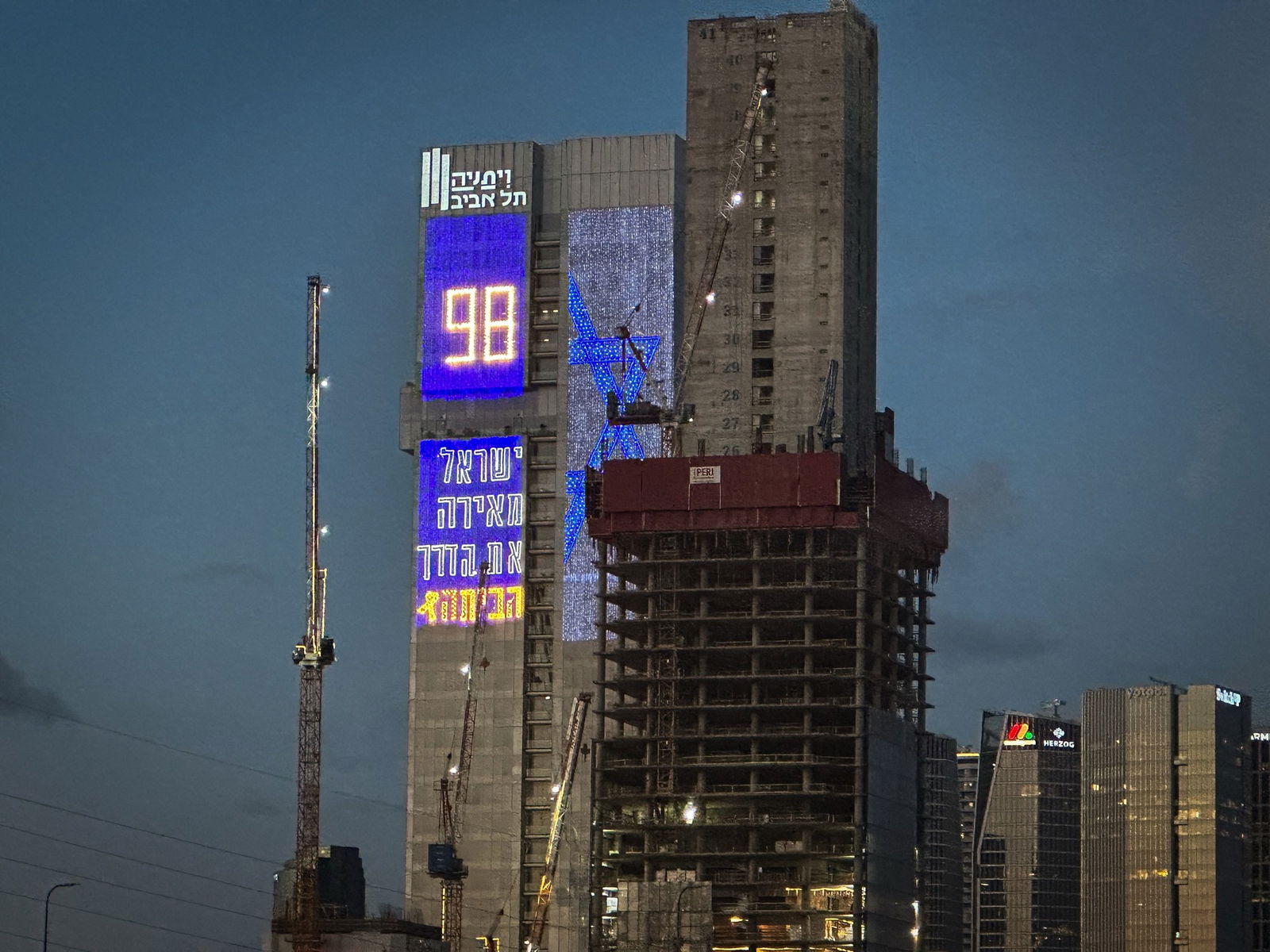 A large building with Hebrew words projected on to the side of it.