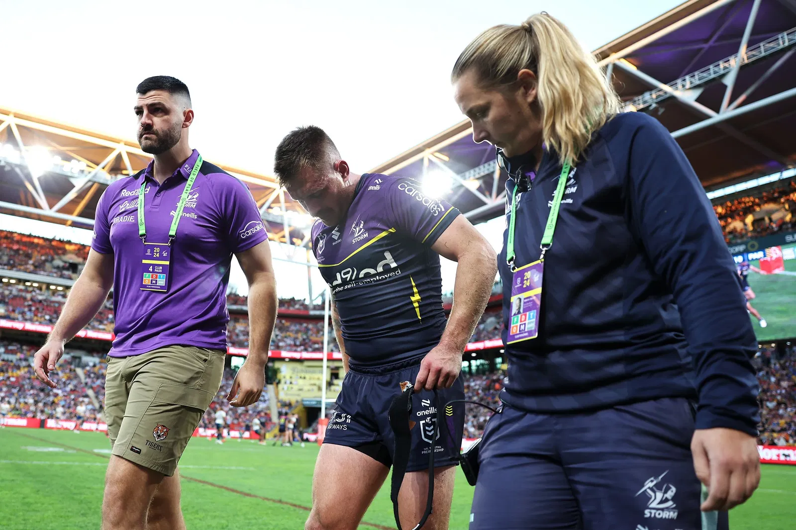 Cameron Munster is helped off the field by Melbourne Storm trainers.