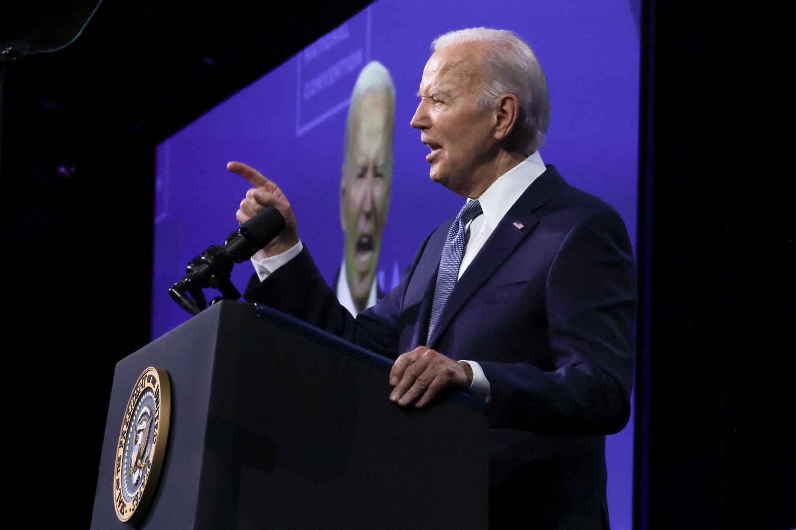 Biden points with his right hand as he speaks at a podium