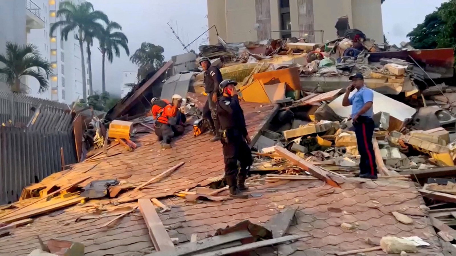 People stand in the rubble of a collapsed building