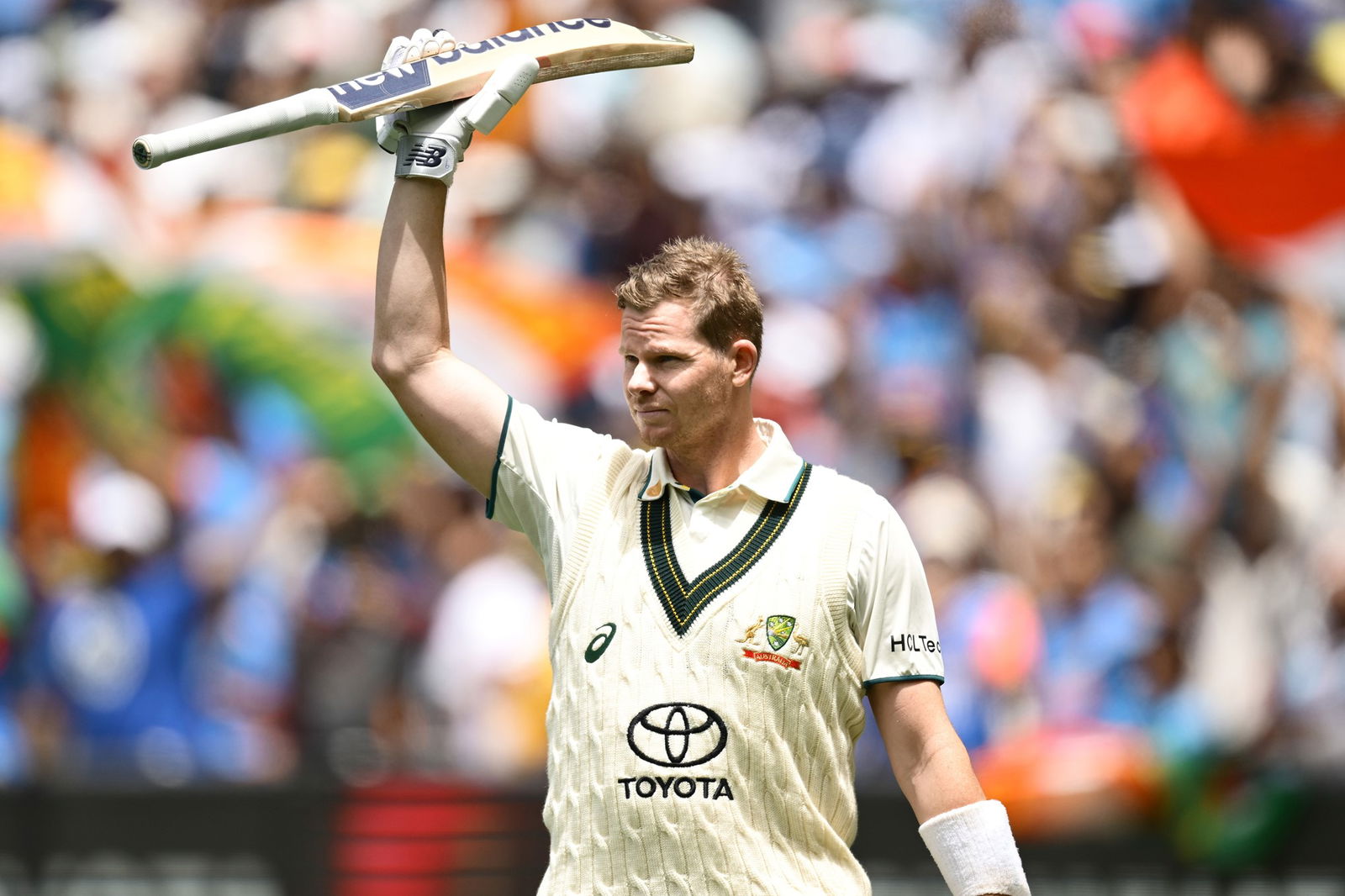 Steve Smith holds his bat in the air during a cricket Test match.