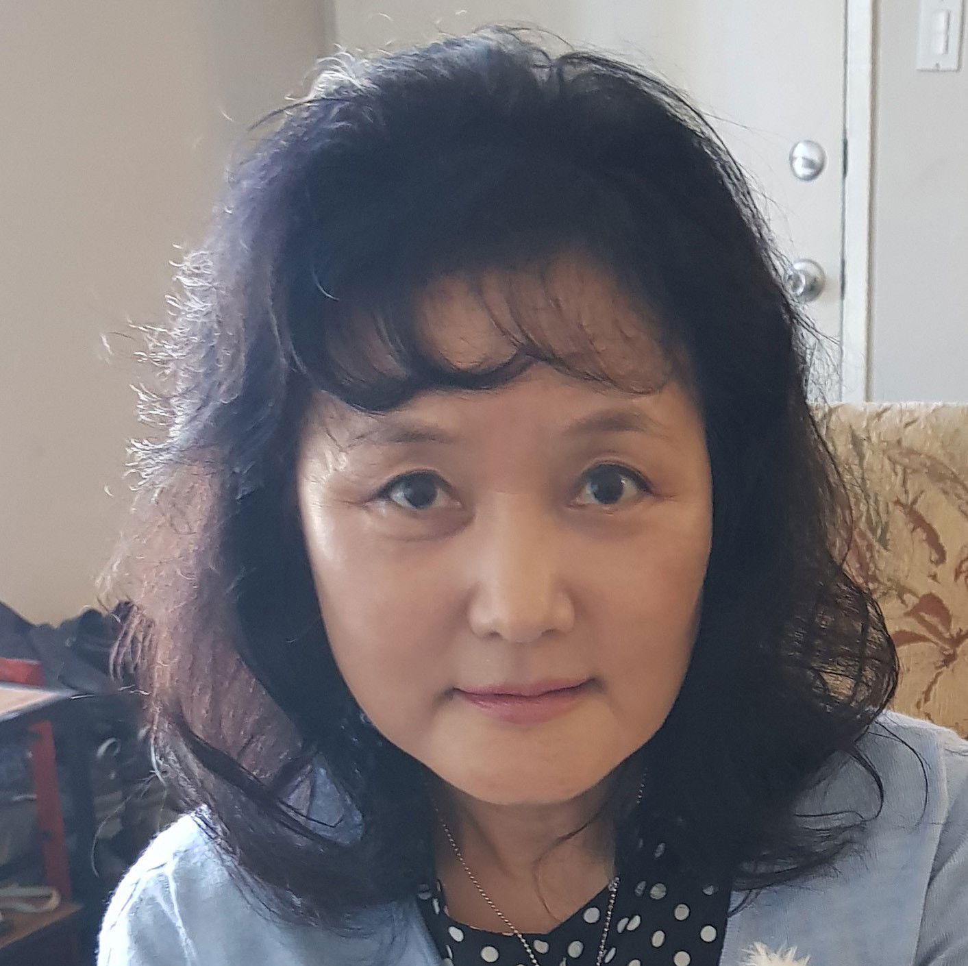 an older Korean woman with blowdried black hair looks directly at the camera