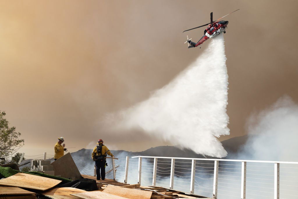 A helicopter drops water on the Palisades Fire near the Sullivan Canyon area of Los Angeles on Saturday, local time. The devastating Palisades Fire pushed to the northeast, has prompted new evacuations in the Southern California neighbourhoods of Brentwood and Encino. Photo /  Getty Images
