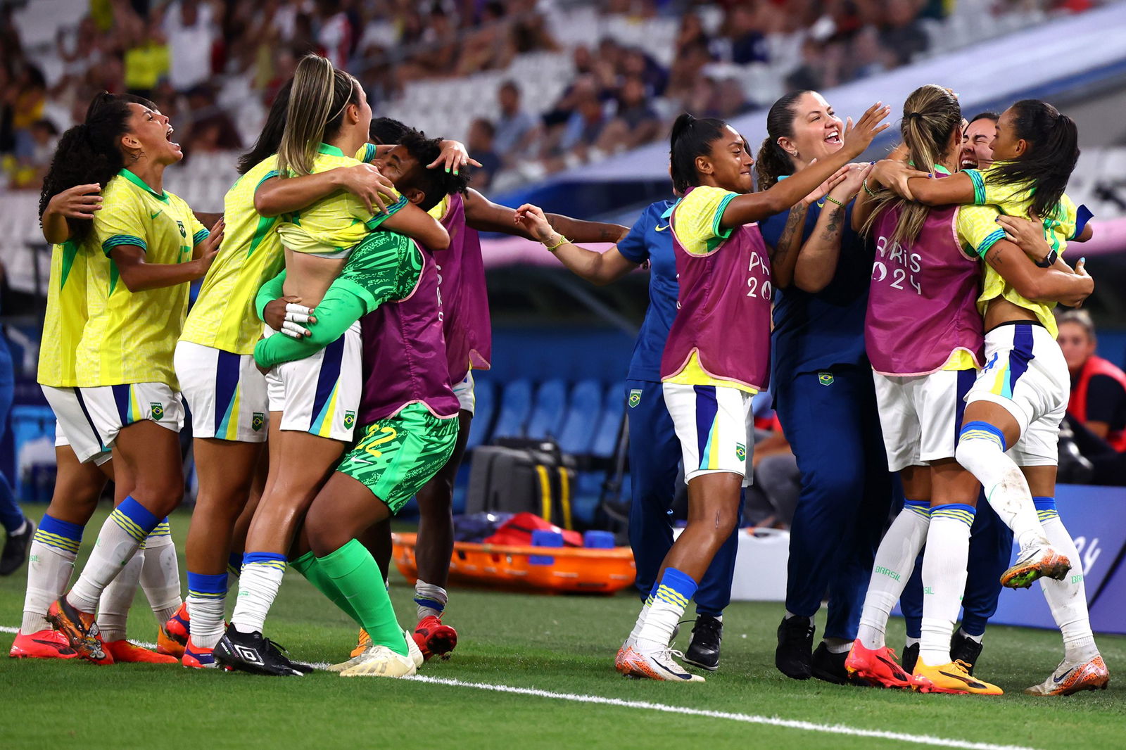 Brazil players hug each other near the sideline after scoring a goal.