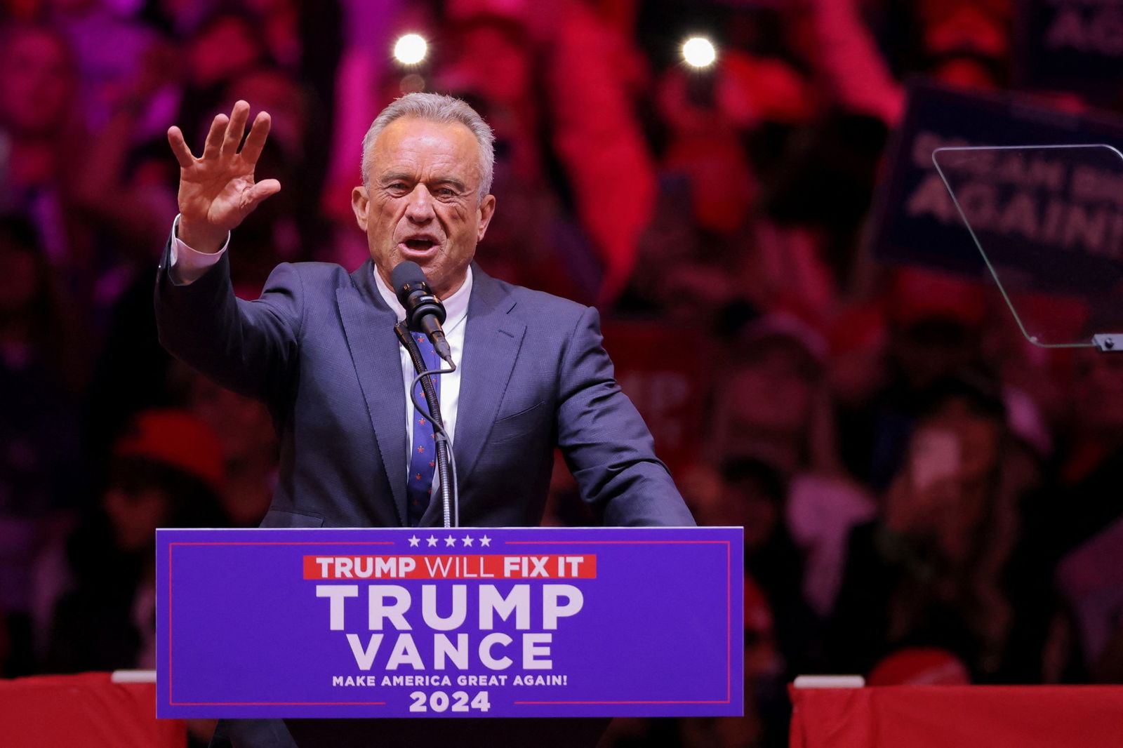 RFK Jr raises a hand as he speaks 