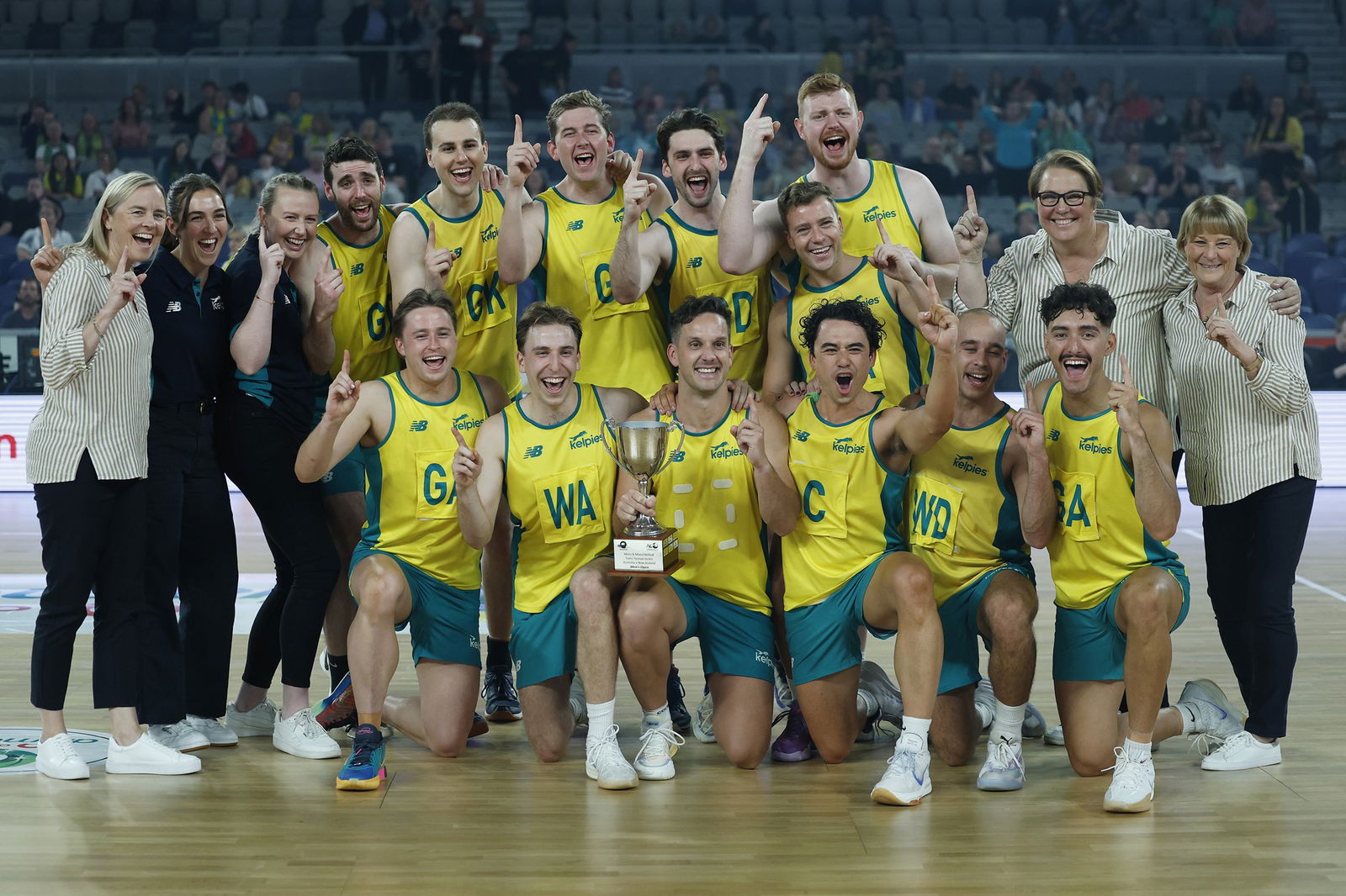 Players huddle together with their coaches and a trophy