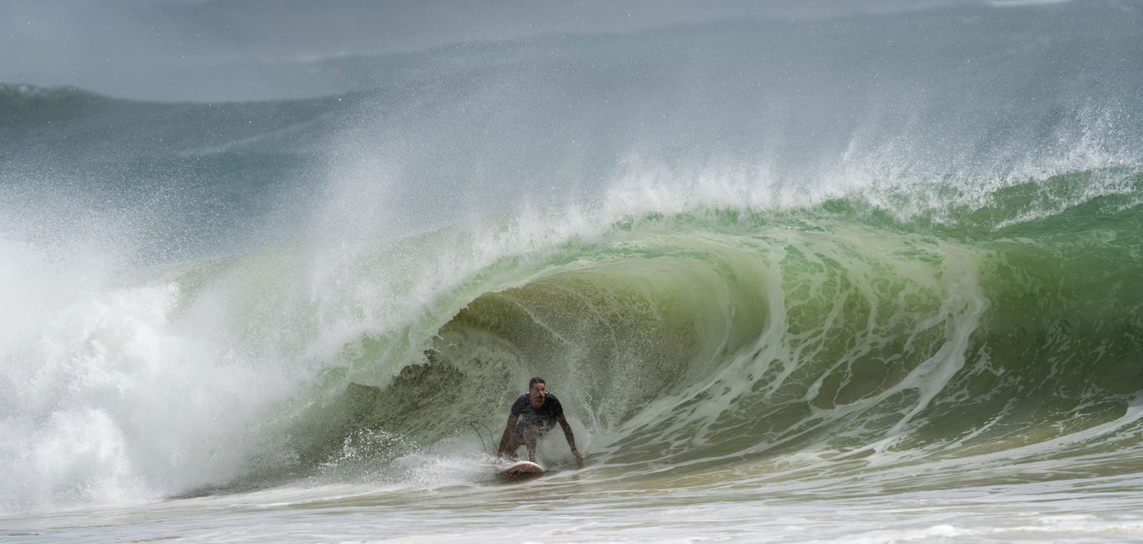 A man surfing a wave full of sand.