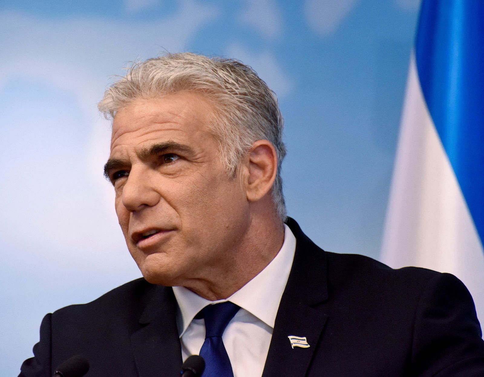 A silver-haired man with a stern expression