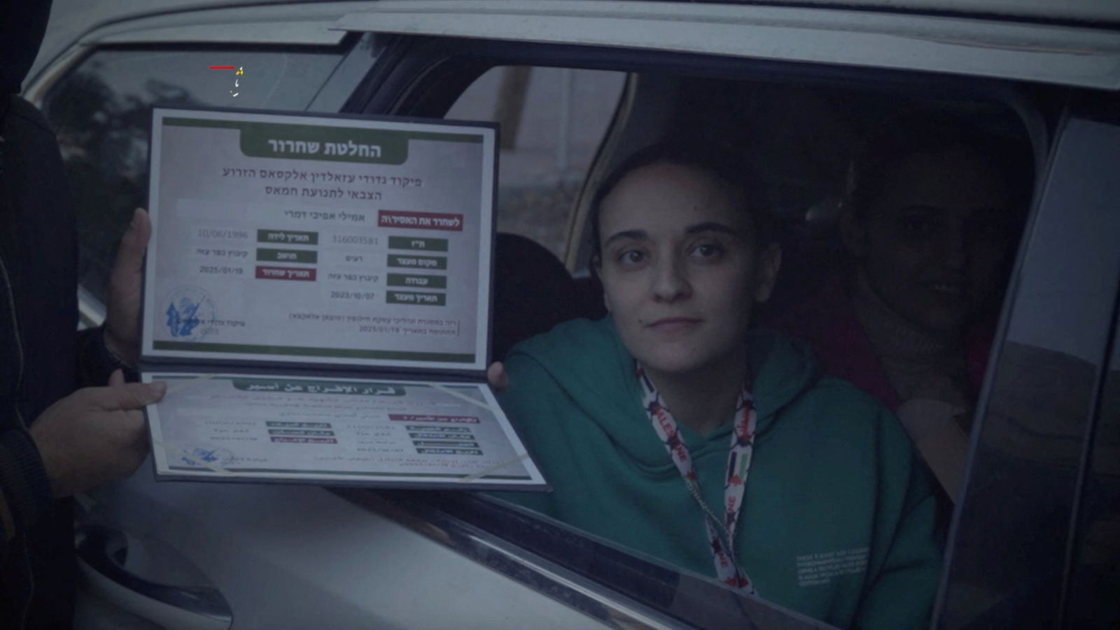 A woman holding a certificate with hebrew writing on it. 