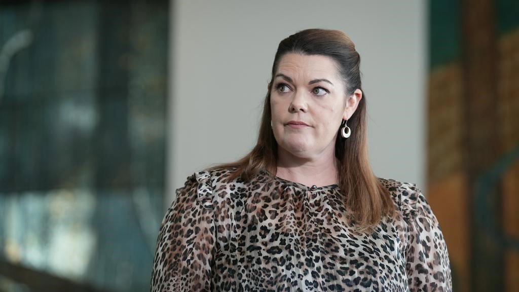 A women looks to the left as she is asked a question.