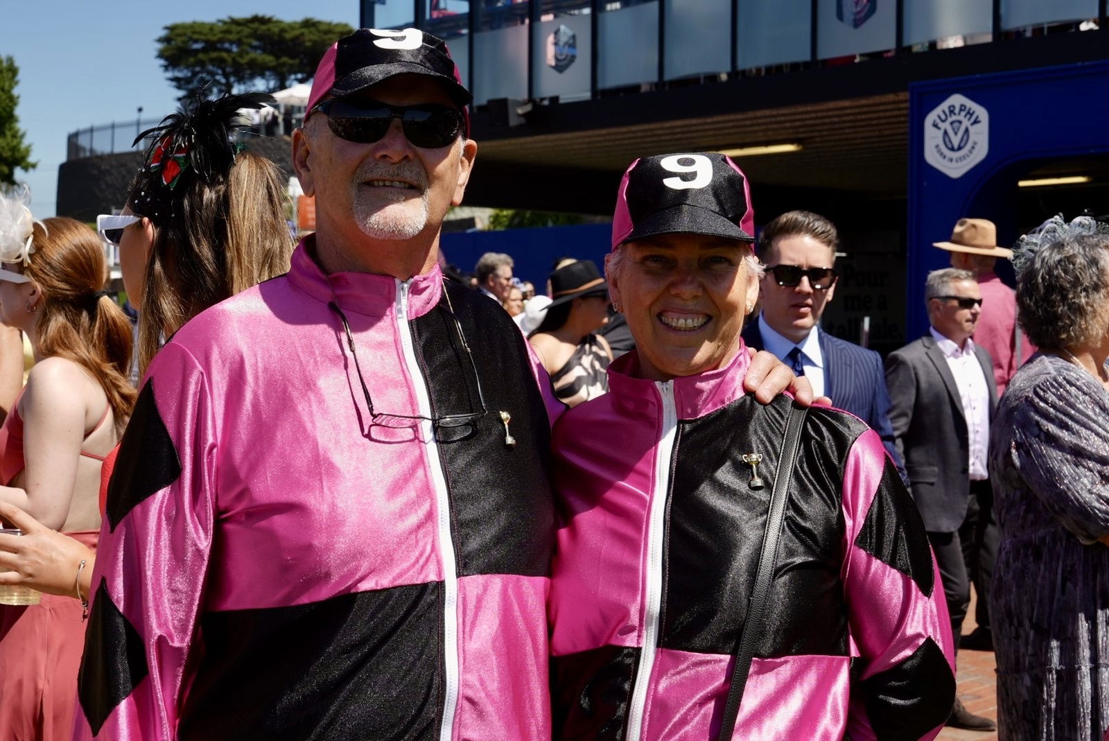 A man and a woman dressed as jockeys smiling at the camera.