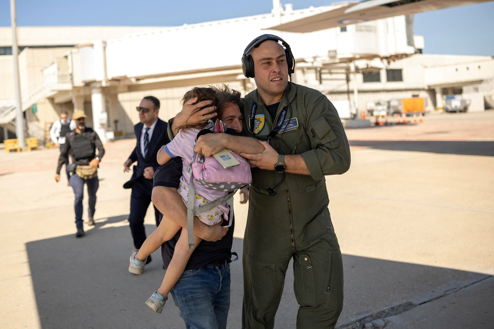 an airforce soldier helps a woman and her toddler onto a plane