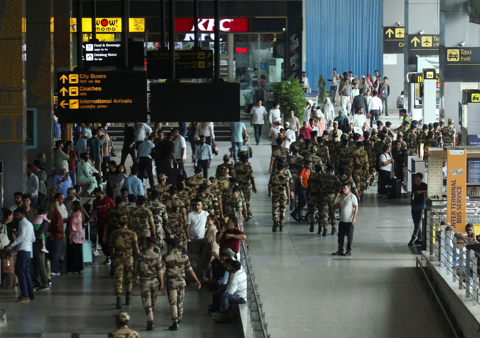 Dozens of military pesonnel in uniform walk through the concourse of an airport