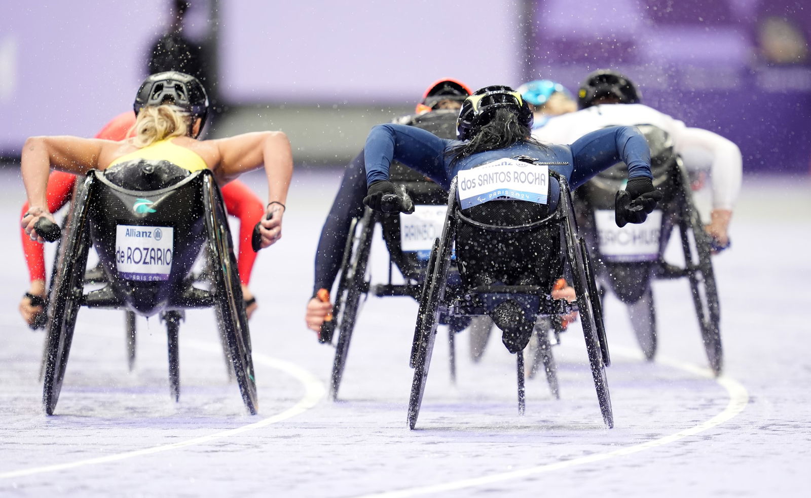 Athletes, including Australia's Madison de Rozario (left) compete in heavy rain in round 1 of the women's 5000m T54 event in Paris.