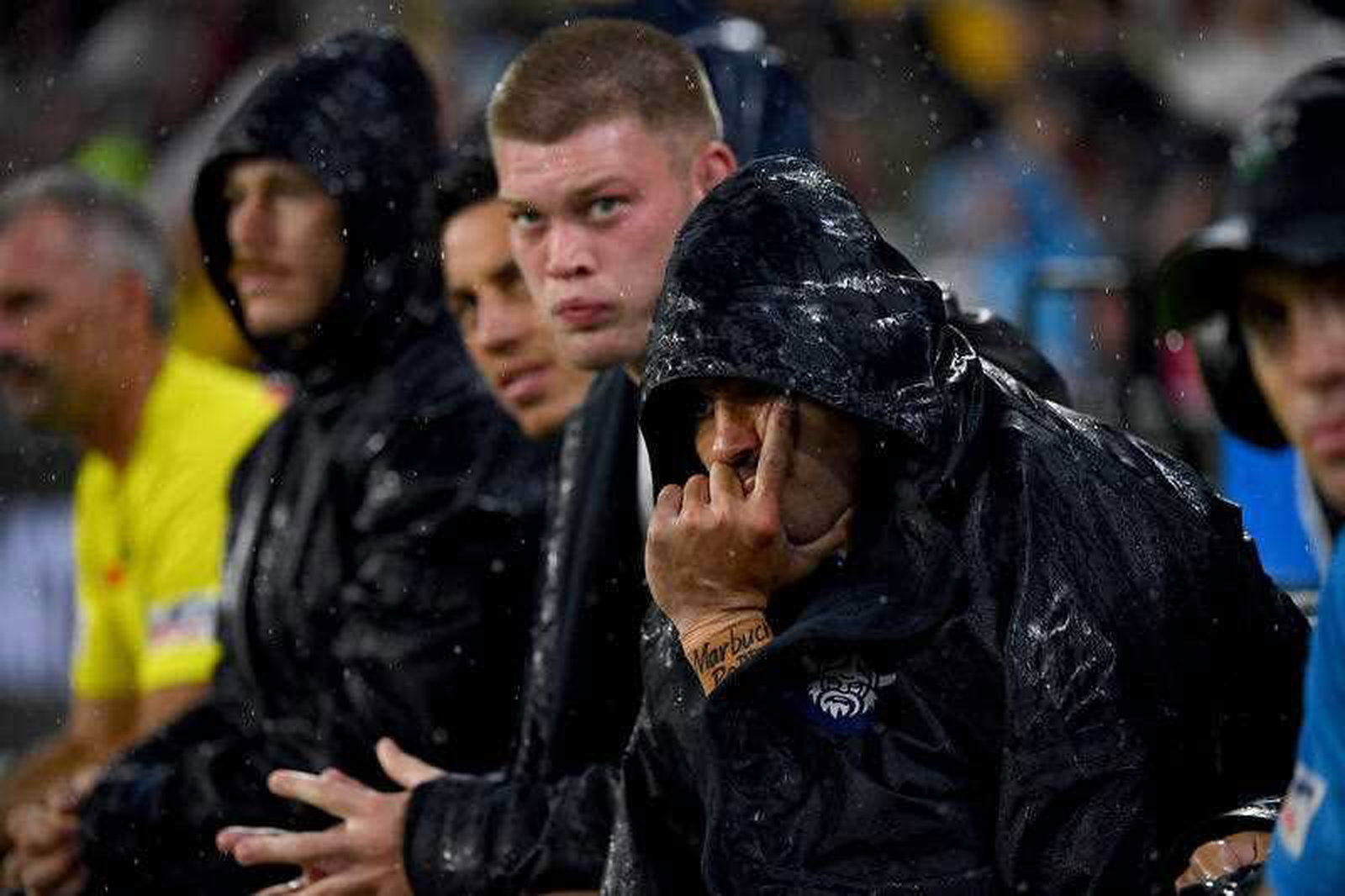 Jamal FOgarty wears a hooded raincoat on the sidelines during an NRL game.