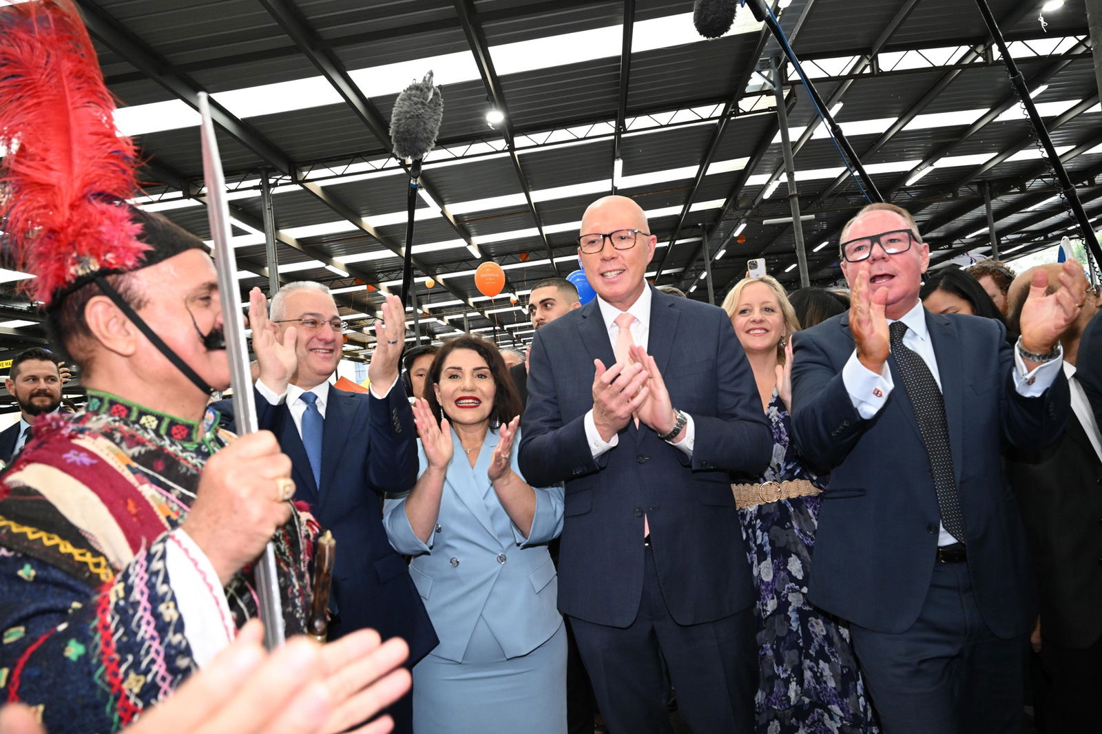 Dutton and people in suits clap hands as they watch a dancer