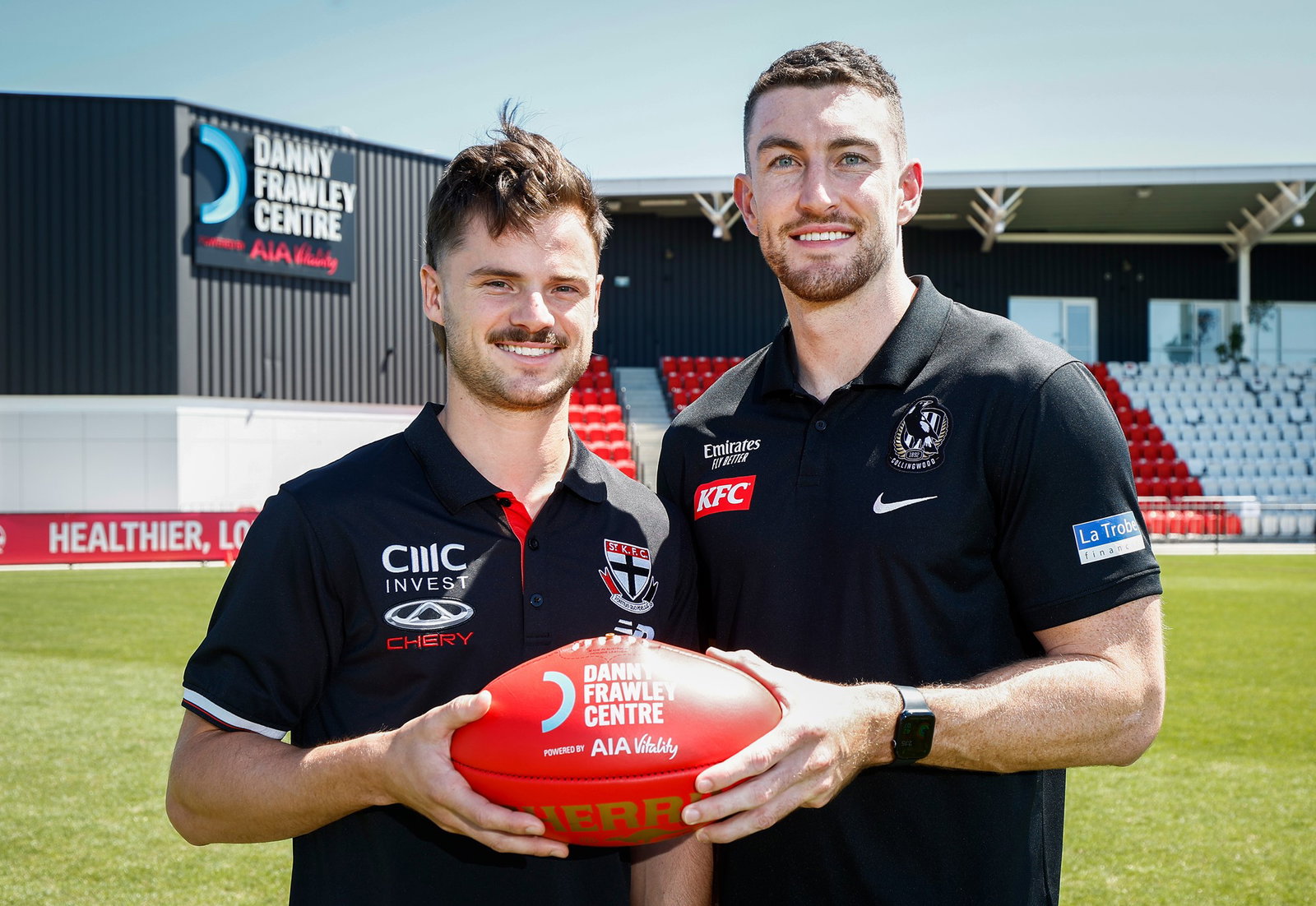 Two footballers hold a ball between them