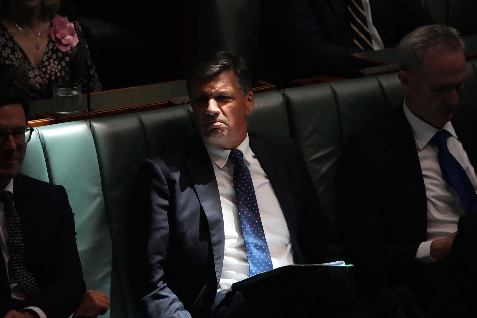 A man in a suit sits in darkness