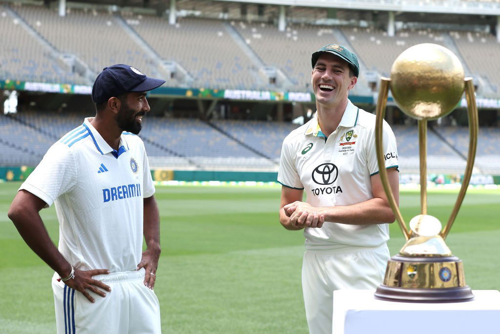 India captain Jasprit Bumrah and Australia captain Pat Cummins smile next to the Border-Gavaskar Trophy.