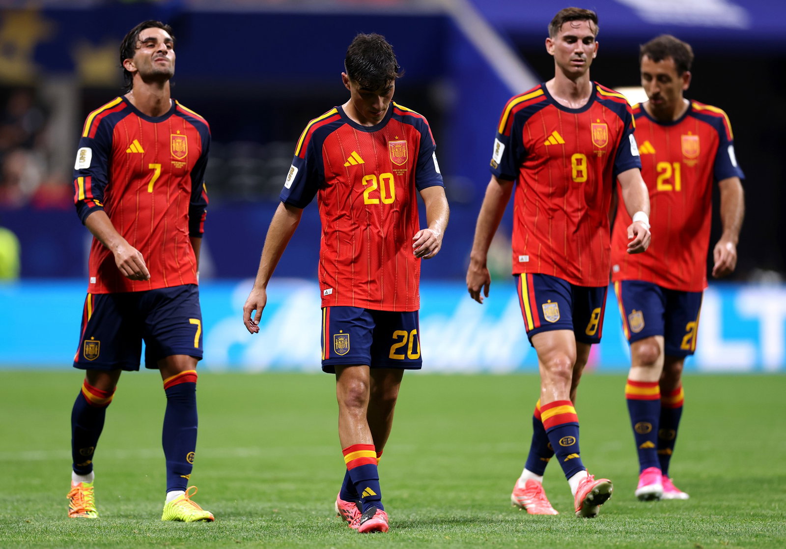 Four soccer players in red walk with glum expressions
