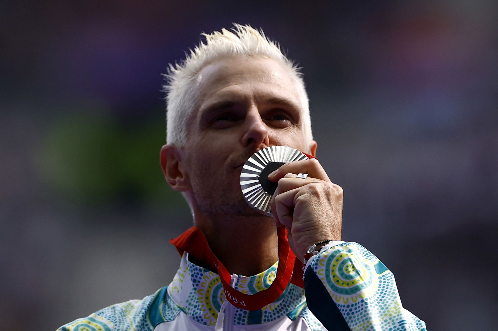 Michael Roeger holds a silver medal up to his lips and kisses it.