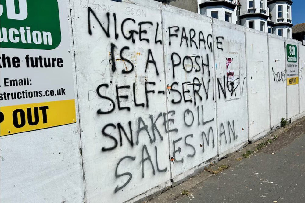 Graffiti on a wall that reads: Nigel Farage is a posh self-serving snake oil salesman.