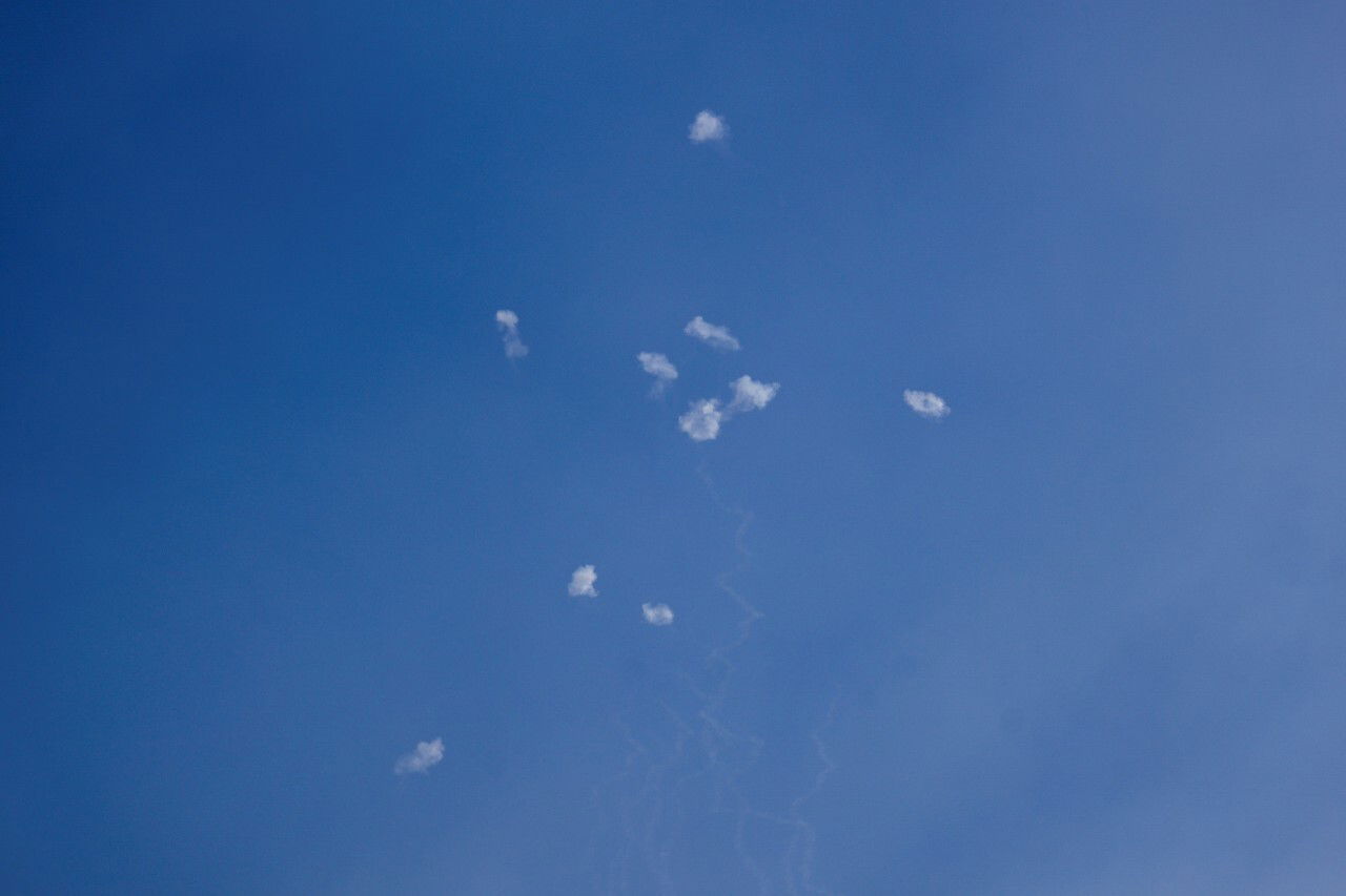 A clear sky, with several plumes of smoke visible.