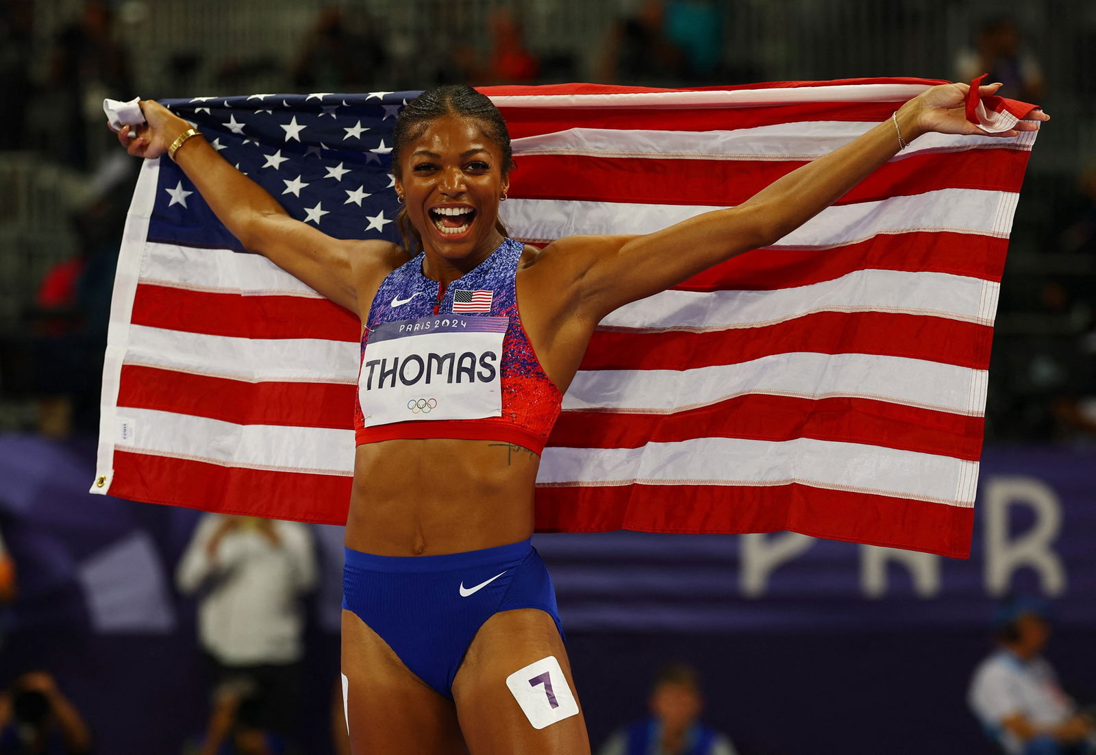 Gabby Thomas holds the YS flag after winning gold.