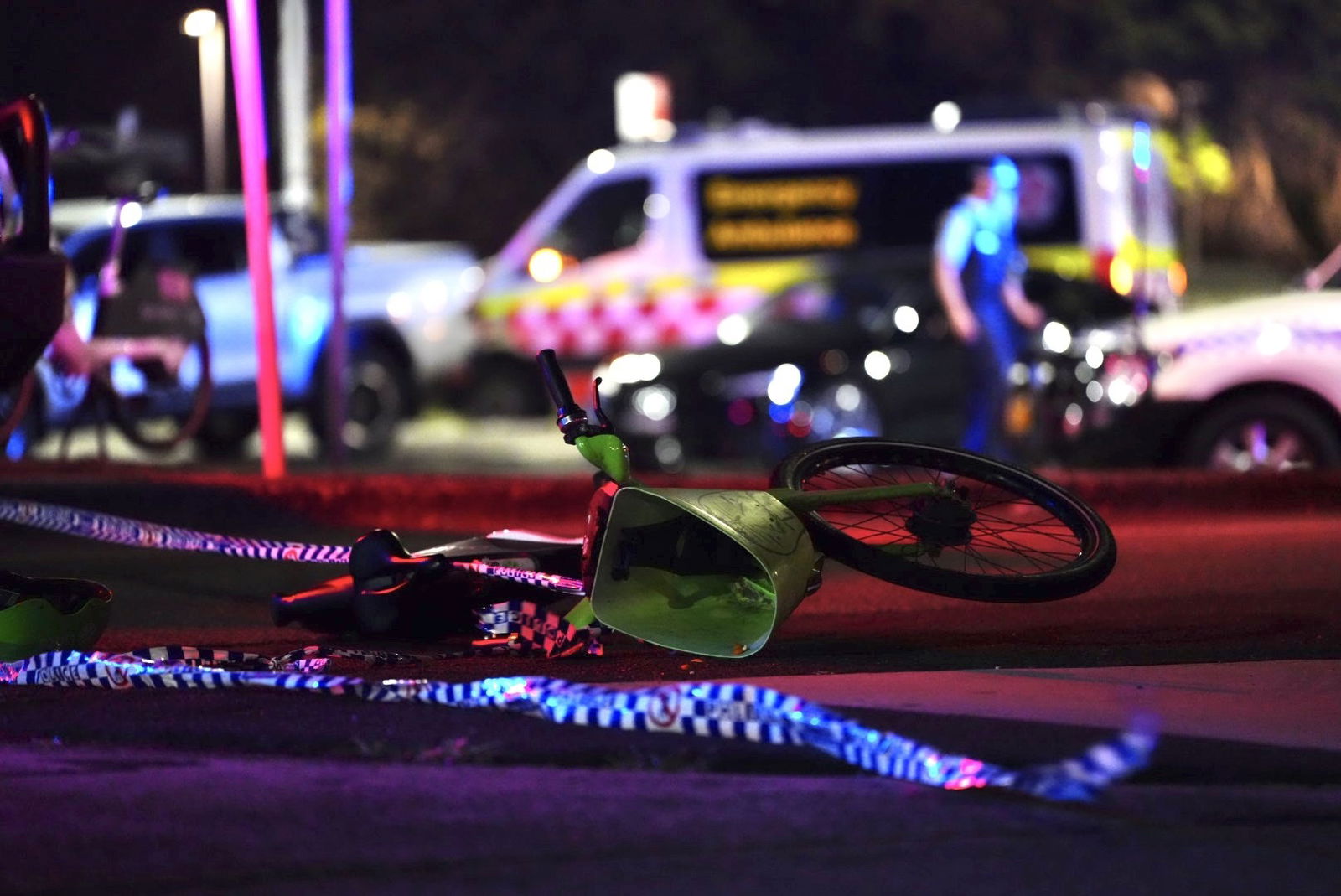A pushbike lies sideways on the road in front of a police operation