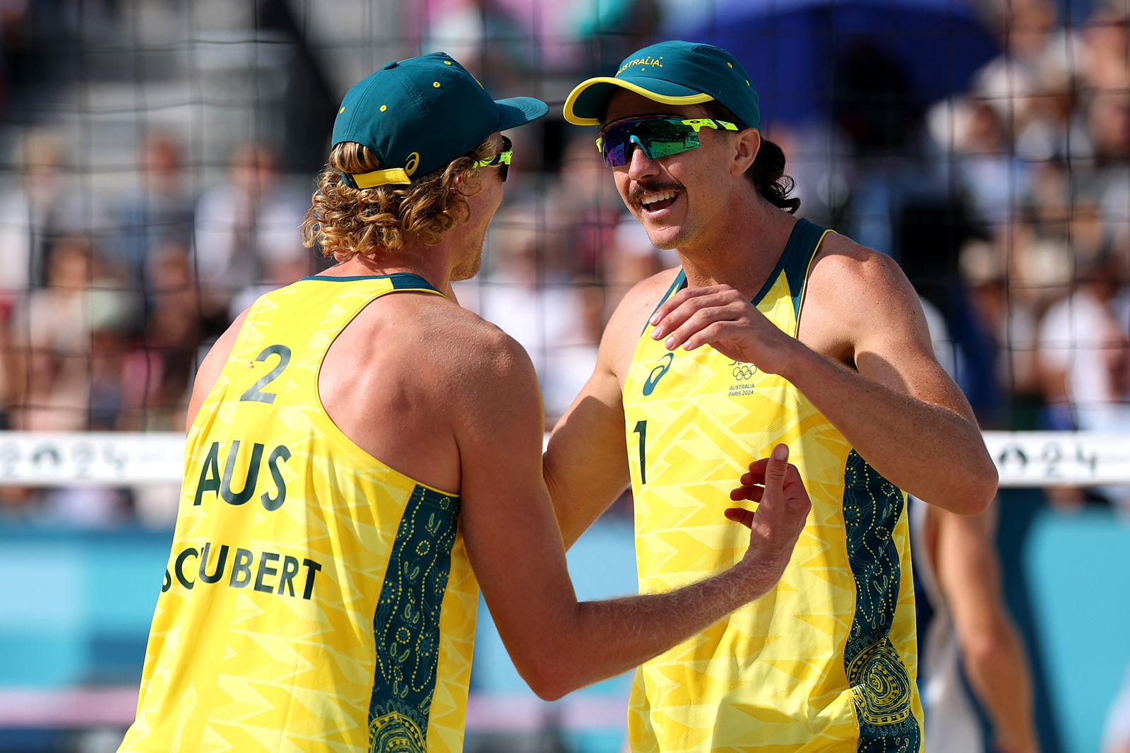Tom Hodges and Zach Schubert hug in the beach volleyball at the Paris Olympics.