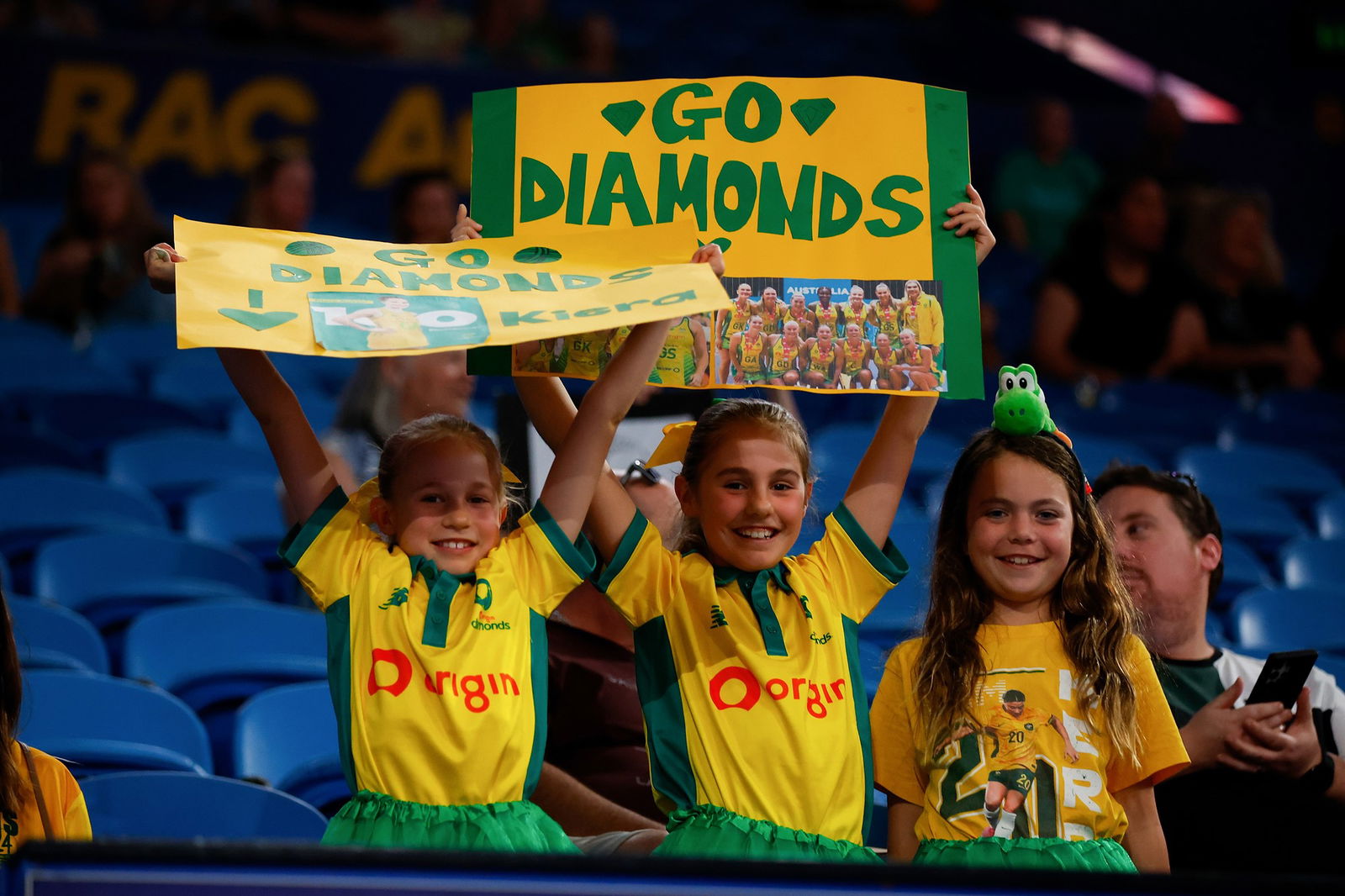 Three young girls hold signs for the Diamonds team