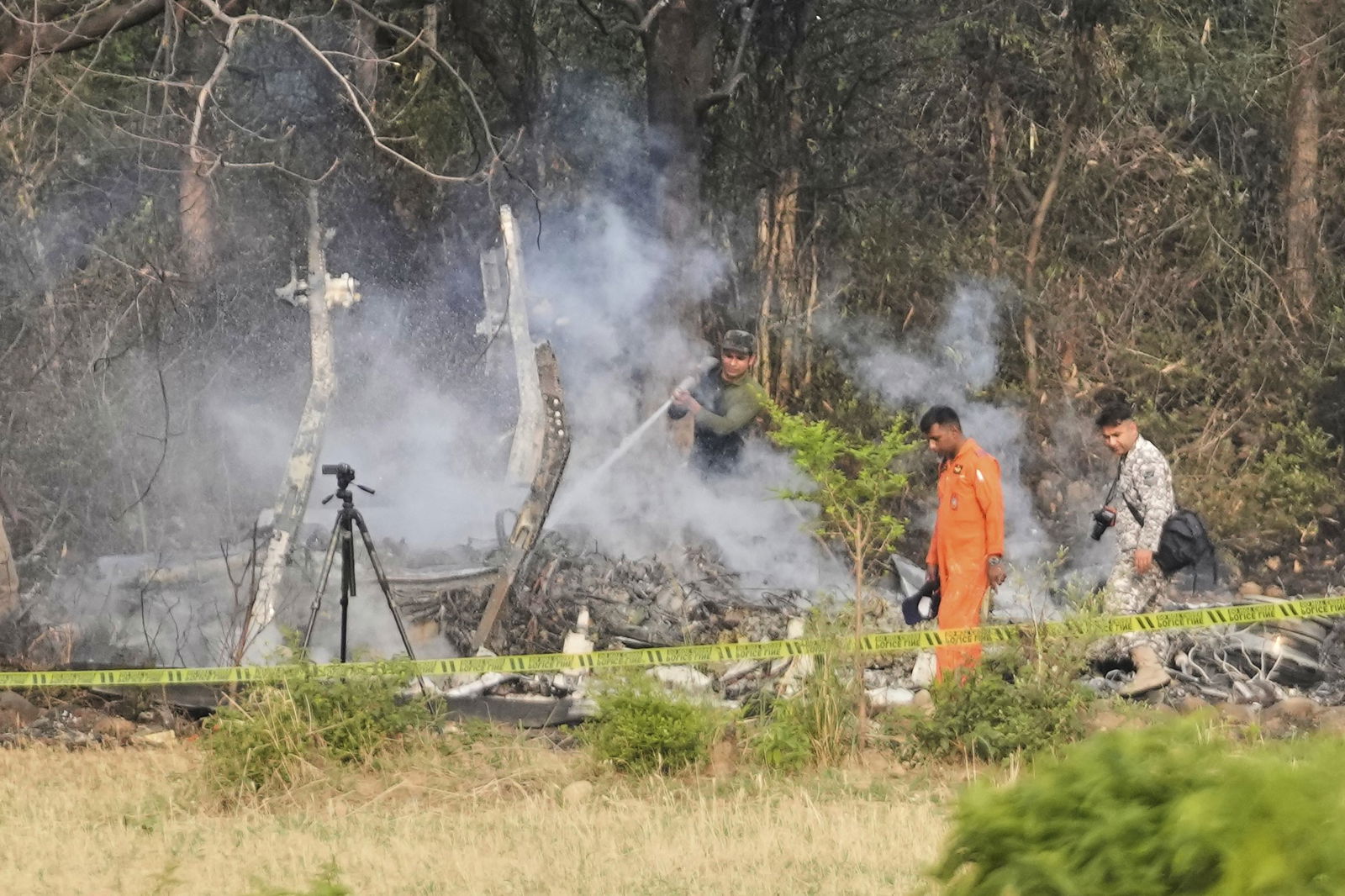Investigators move through the smoulering wreckage of a plane near trees