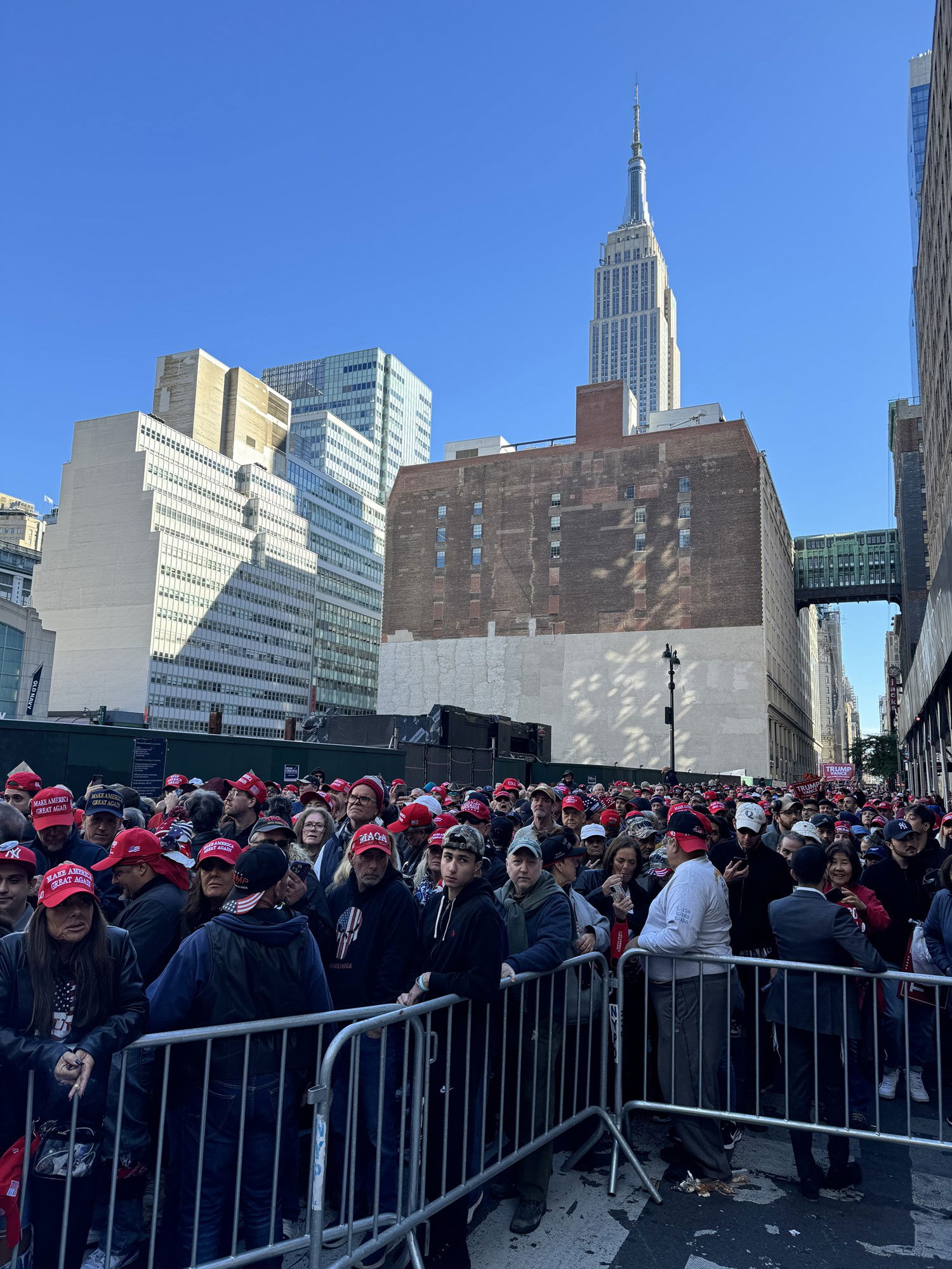 A long line of Trump supporters waits on a New York street, with the Empire State building in the background. 