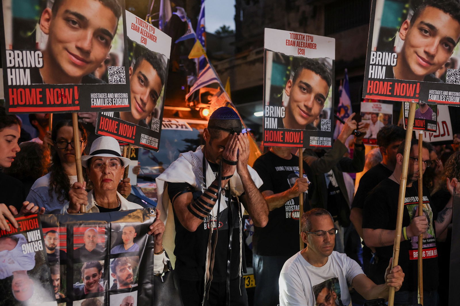 A group of people holding signs with faces, one with their head in their hands