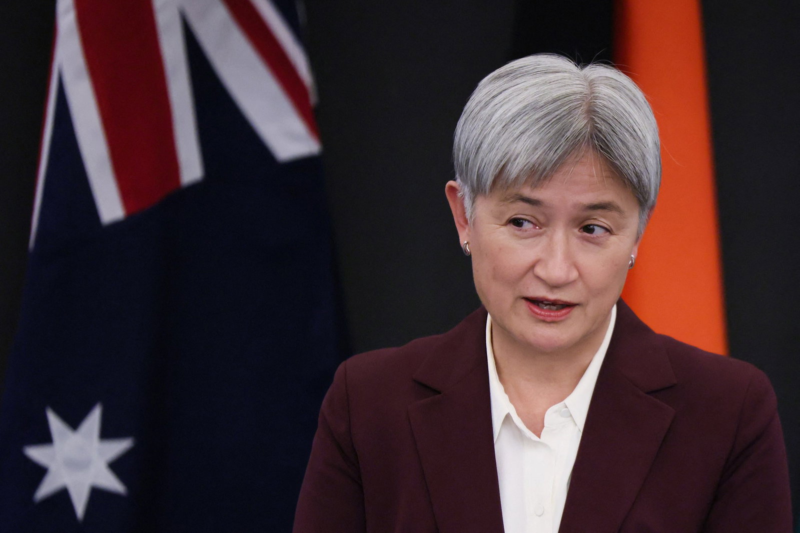 Penny Wong speaks while standing in front of a Australian flag.