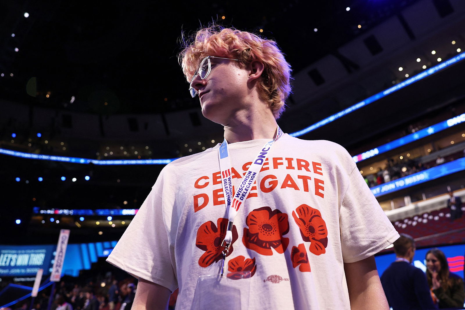 A man with pink hair wears a t-shirt that says Ceasefire Delegate.